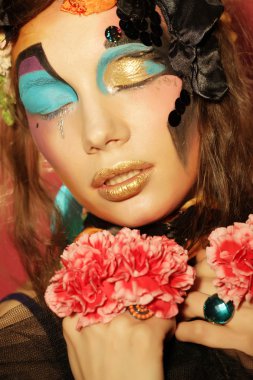 Yaratıcı makyajlı kadın pembe çiçekleri tutuyor.