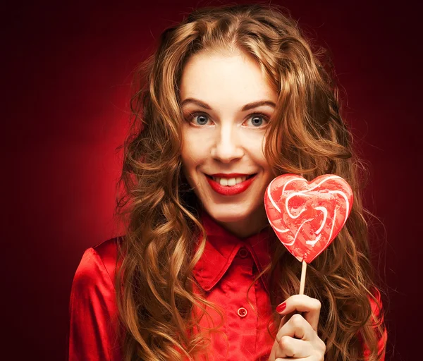 Mulher com caramelo coração sobre fundo vermelho — Fotografia de Stock