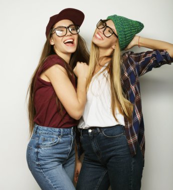 İki genç kız arkadaş birlikte durup eğleniyorlar.