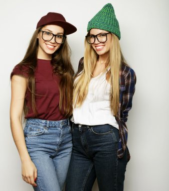 İki genç kız arkadaş birlikte durup eğleniyorlar.