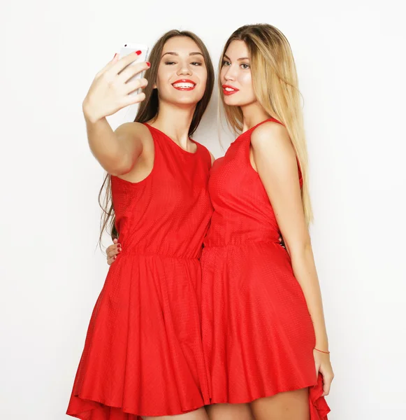 Две женщины в красном платье делают селфи — стоковое фото