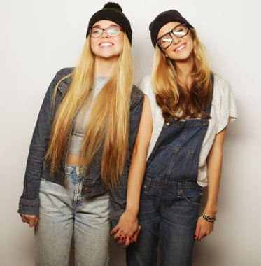 İki genç kız arkadaş birlikte durup eğleniyorlar.