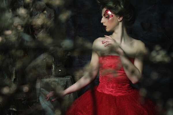 Portrait of a beautiful blond woman in red dress. Creative make up and hairstyle. Shot in a fantasy house.