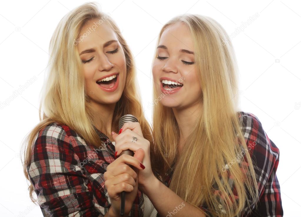 two beauty girls with a microphone singing and having fun