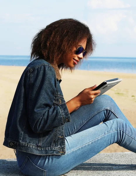 Африканская американская молодая женщина с планшетом на пляже — стоковое фото