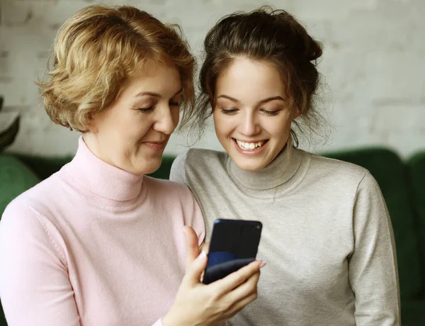 Famiglia, persone e tecnologia. Donna anziana e sua figlia adulta utilizzando smartphone a casa. — Foto Stock