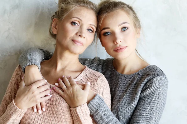 Hermosa mamá mayor y su hija adulta están abrazando, mirando a la cámara y sonriendo. —  Fotos de Stock