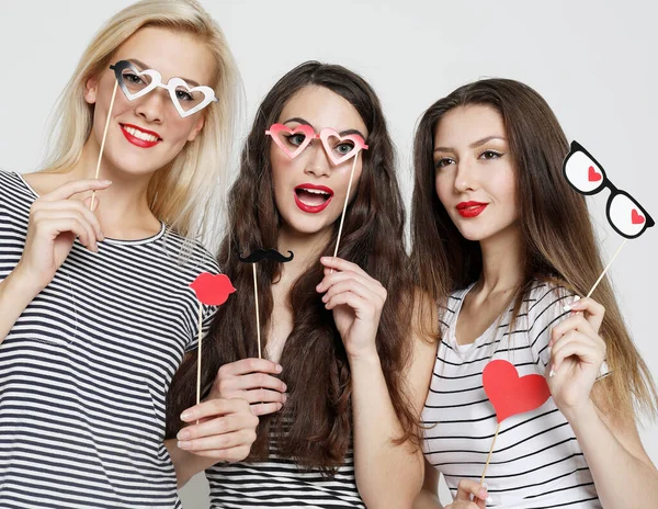 Tres mujeres jóvenes sosteniendo palos de fiesta de papel — Foto de Stock