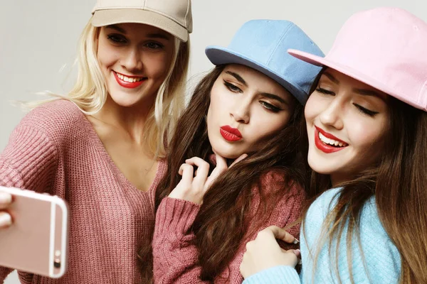 Trois heureuses meilleures copines portant des pulls et des casquettes faisant du selfie — Photo