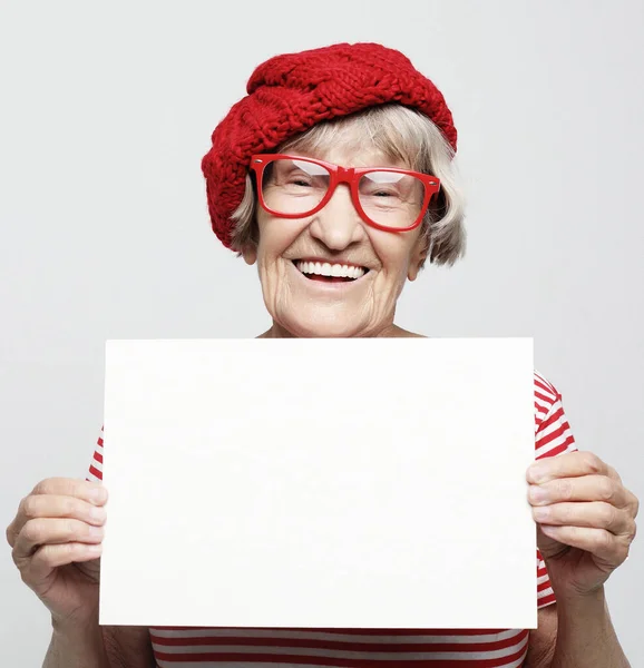 Retrato de mujer mayor feliz con tablero de publicidad en blanco o espacio de copia, sobre fondo gris claro — Foto de Stock