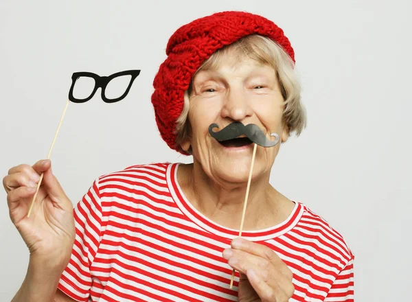 Lifestyle and people concept: funny grandmother with fake mustache and glasses, laughs and prepares for party — Stock Photo, Image
