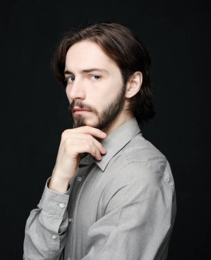 Mutsuz adam siyah arka planda alnına dokunuyor.