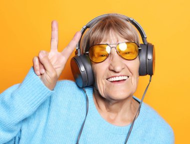 Müzik dinleyen ve baş parmağını kaldıran komik yaşlı kadın..