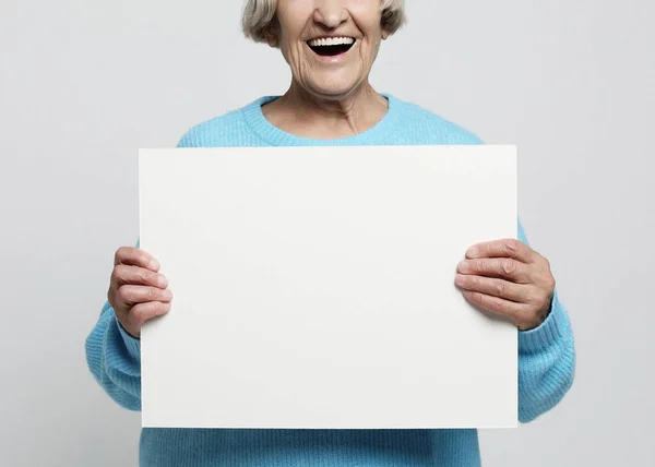 Aged woman with blank advertising board or copy spacet. — Stock Photo, Image
