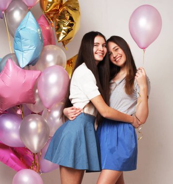 Yaşam tarzı, insanlar, gençler ve arkadaşlık konsepti - Beyaz arka planda balonları olan güzel genç kızlar