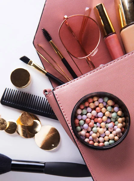 Concetto di moda e bellezza: posa piatta della borsa donna in pelle rosa aperta con cosmetici e accessori su sfondo bianco. — Foto Stock
