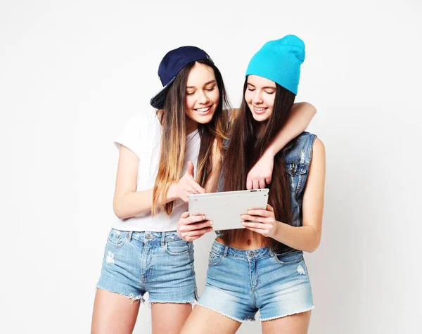 Dos amigas jóvenes casuales con tableta digital sobre fondo blanco —  Fotos de Stock