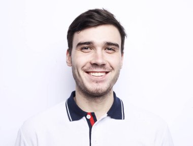 Mutlu adam kameraya bakıyor ve beyaz arka planda gülümsüyor.