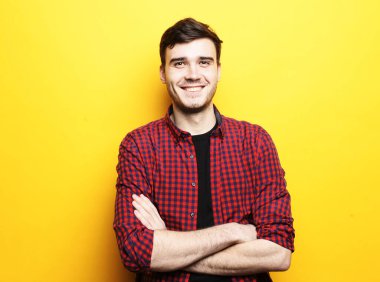 Sarı arka planda duran gülümseyen genç adam