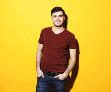 Sarı arka planda duran gülümseyen genç adam