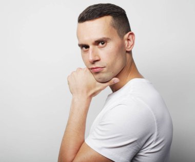 Yaşam tarzı ve insan konsepti: Beyaz arka planda sıradan giyinmiş zeki bir gencin portresi