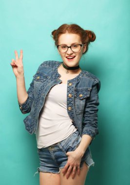 Gayri resmi giyinen güzel kızıl saçlı kadın zafer ya da barış işareti gösteriyor.