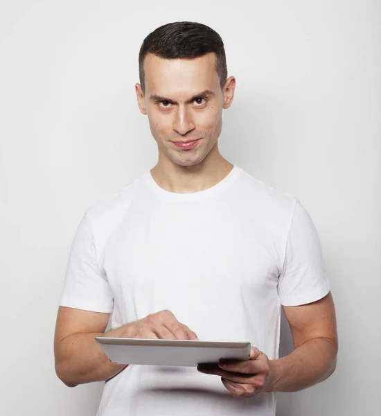 Ung man i vit t-shirt med hjälp av en surfplatta dator — Stockfoto