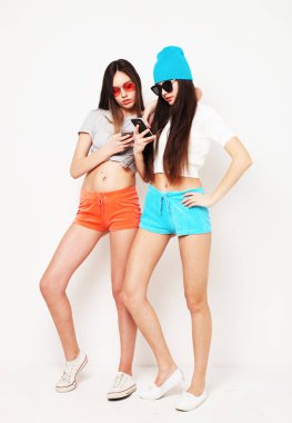 İnternette gezinen ya da beyaz arka planda izole edilmiş cep telefonu kullanan iki hippi kadın.