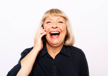 Neşeli başarılı 60 yaşında sarışın bir kadın telefonda konuşuyor.