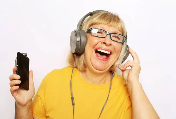 Весела літня жінка слухає музику з навушниками білий фон — стокове фото