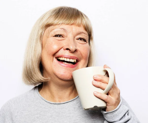 Cheerful elderly woman with cute smile holding a cup isolated on white background