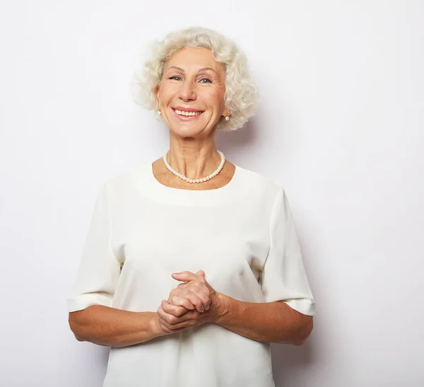 Veselá starší žena stojí na bílém pozadí — Stock fotografie