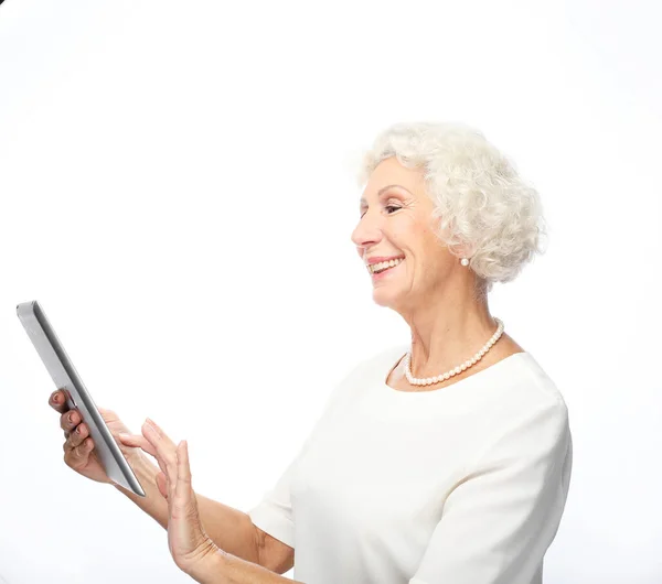 Женщина 65 лет, держащая в руках планшетный компьютер на белом фоне — стоковое фото