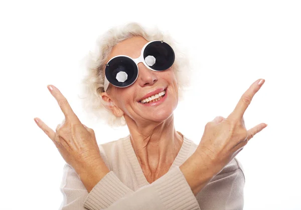 Elderly woman wearing big sunglasses doing funky action isolated on white background — Stock Photo, Image