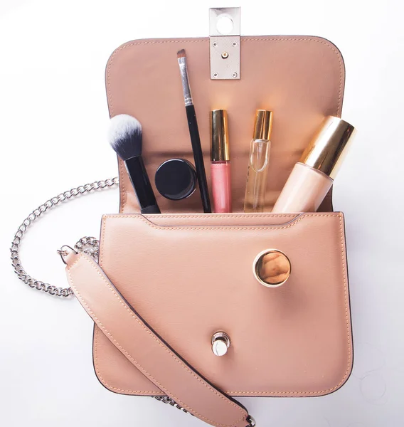 Concetto di moda e bellezza: posa piatta della borsa donna in pelle rosa aperta con cosmetici e accessori su sfondo bianco. — Foto Stock