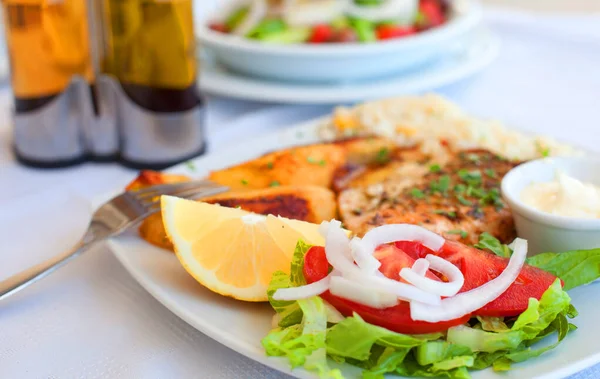 Греческая еда - лосось на гриле и овощи на белой тарелке — стоковое фото