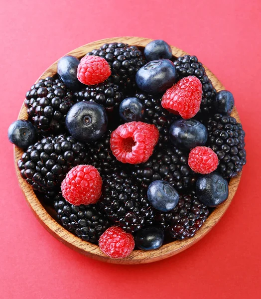 Frische Beeren Salat in einem Holzteller auf rotem Hintergrund. — Stockfoto