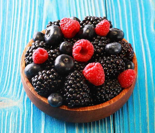 Fresh berries salad in a wooden plate on blue background. Flat lay, top view — Stock Photo, Image