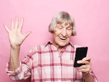 Yaşlı büyükannesi torunlarıyla telefonda konuşuyor, gülümsüyor ve onları selamlıyor..