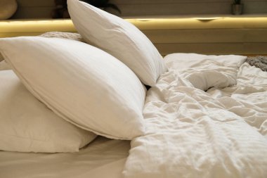 Yatak odasında yatak, beyaz yastıklar ve rahat çarşaflar.