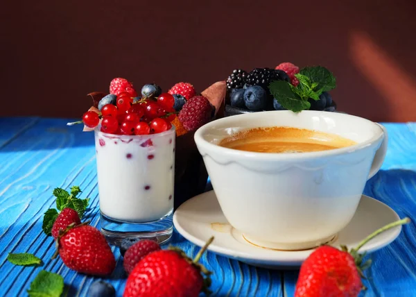 Morgonfrukost. Cupcake med bär, en kopp kaffe och yoghurt med röda vinbär — Stockfoto