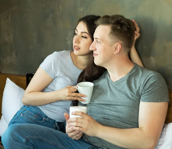 Νεαρό ευτυχισμένο ζευγάρι πίνει καφέ στο κρεβάτι το πρωί — Φωτογραφία Αρχείου