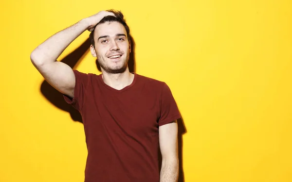 Handsome young man in blank red shirt posing over yellow background — Stock Photo, Image