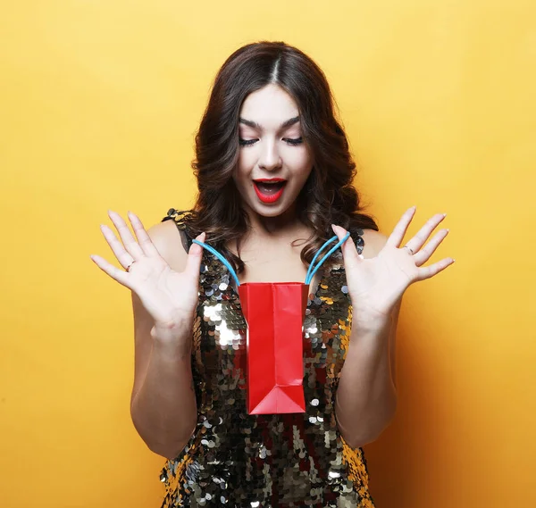 Beautiful young woman holding a red gift bag, anticipation of surprise, joy and happiness