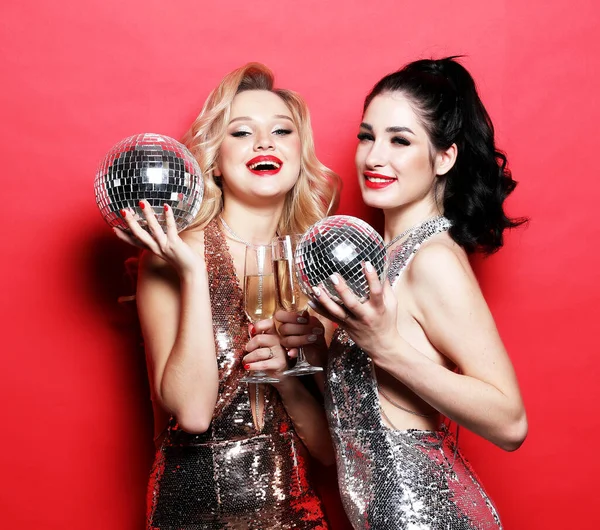 Dos mujeres glamour, novias en lujoso vestido de lentejuelas brillo y brillante rostro sosteniendo bolas de discoteca y copa de vino, —  Fotos de Stock