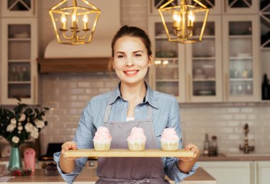 Genç fırıncı kadın elinde kek tutuyor..