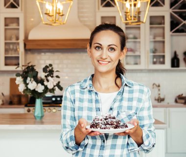 Çikolata parçacıklı kurabiyelerle dolu tabağı tutan güzel bir genç kadın..