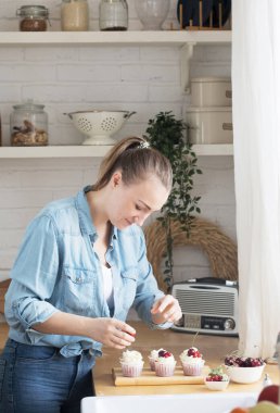 Genç kadın pasta şefi kekleri süslüyor.