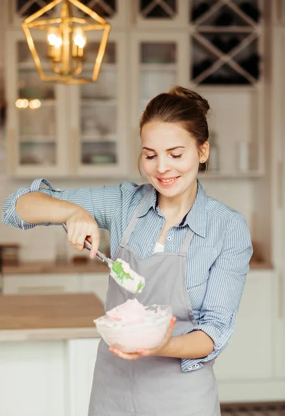 Young woman mixes cake cream using a spatula — Stock Photo, Image