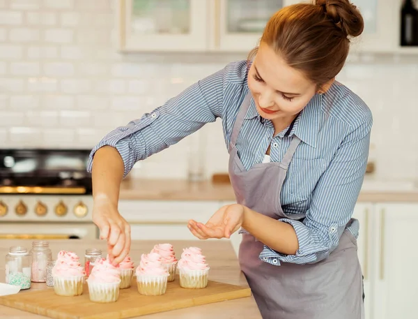 Young woman decorates cupcakes. Unicorn style. Pink color. A beautiful treat for a childrens party. — Stock Photo, Image